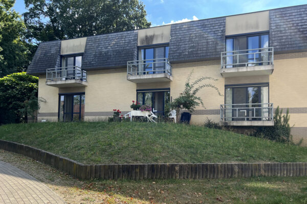 De achterkant van woonzorgcentrum Beerzelhof, waar zichtbaar is dat elke kamer beschikt over een terras met uitzicht op de tuin.